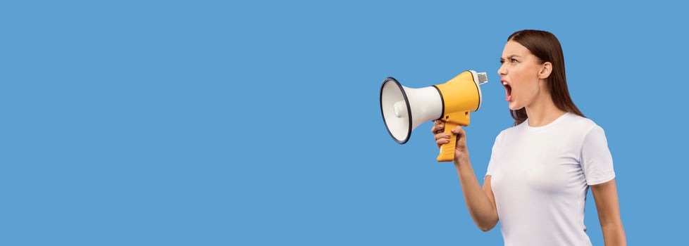 Full length portrait of aggressive young woman shouting using megaphone isolated over purple studio wall, copyspace photo