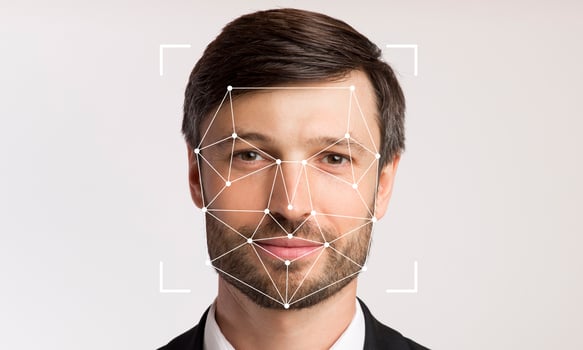 A man with a neutral expression stands against a plain background, displaying facial recognition technology that detects his facial features for identification purposes. photo