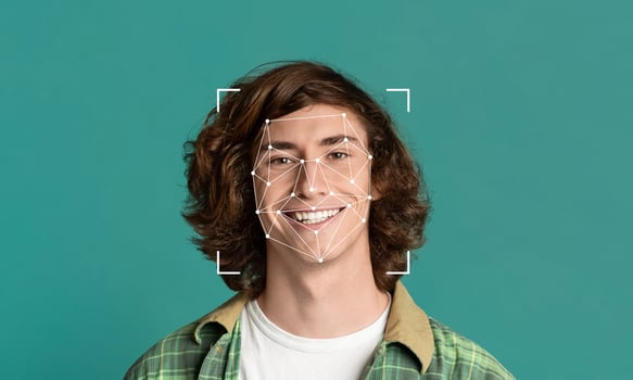 A young individual with curly hair smiles at the camera while a facial recognition overlay highlights key features. This demonstrates advanced identification technology in a simple, clean environment. photo