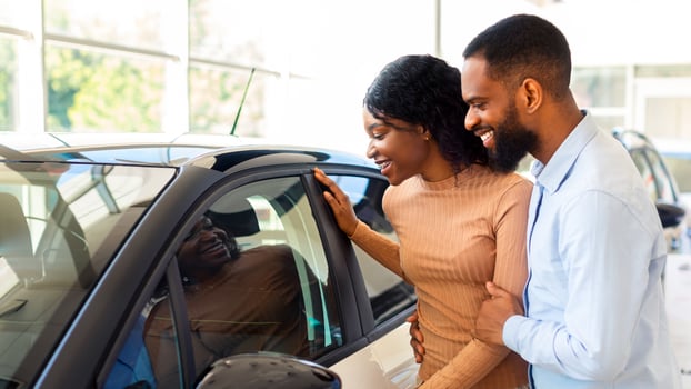 Portrait Of Happy Black Couple In Dealership Center Choosing New Automobile, Cheerful African American Spouses Checking Vehicle Characteristics And Interior, Purchasing Auto In Showroom, Closeup photo