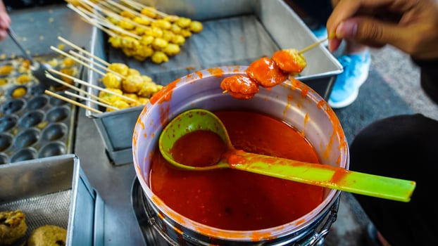 Street Vendor Preparing Skewered Meatballs with Spicy Sauce photo