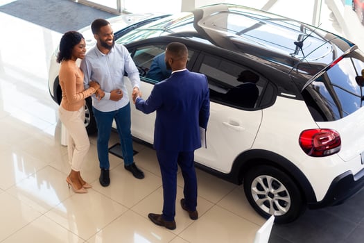 Car Dealership. Top View Shot Of Customers Couple And Black Male Manager Handshaking After Successful Deal In Auto Salon, African American Spouses Purchasing Luxury Automobile In Showroom photo
