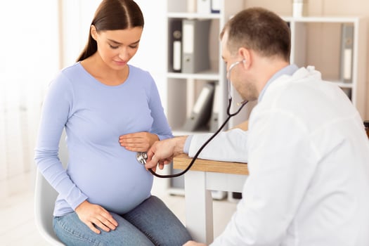 Medical Service Concept. Doctor Examining Pregnant Woman's Belly Using Stethoscope, Listening Baby's Heartbeat In Office photo