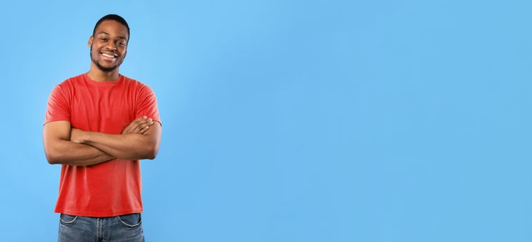 Cheerful African American Guy Smiling To Camera Posing Crossing Hands Standing Over Blue Background. Studio Shot Of Happy Self-Confident Black Millennial Man Expressing Positive Emotions photo
