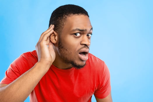 Huh, What Did You Say. African American Guy Listening Holding Hand Near Ear Over Blue Studio Background, Looking At Camera. Man Making I Don't Hear You Gesture. Speak Up, Overhearing Concept photo