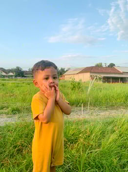 little boy is playing in high weed photo