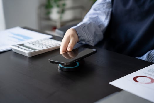 Asian Woman charging smartphone using magnetic wireless charger. photo