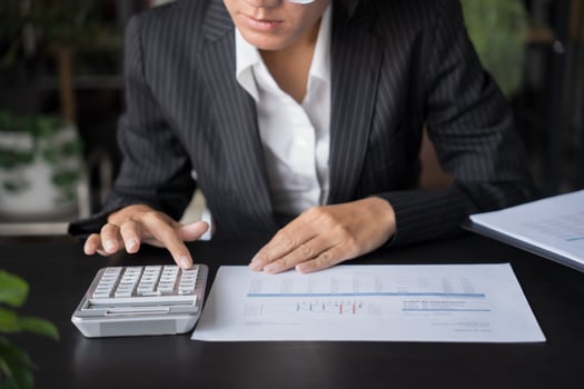 a woman in a suit and glasses is using a calculator photo