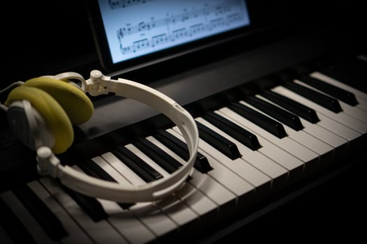 White headphones placed on the black and white keys of an electric piano and a tablet screen. photo