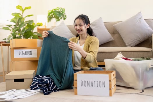 Happy woman sorting clothes for donation in a cozy living room, organizing her wardrobe for a good cause photo