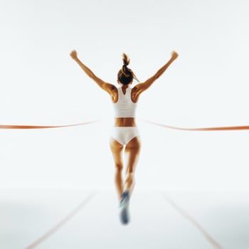 Female athlete crossing the finish line with arms raised in celebration during a track and field event photo