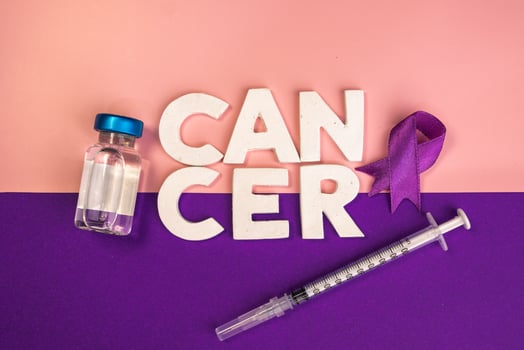 A vial sits next to the word CANCER and a purple ribbon. World cancer day concept background photo