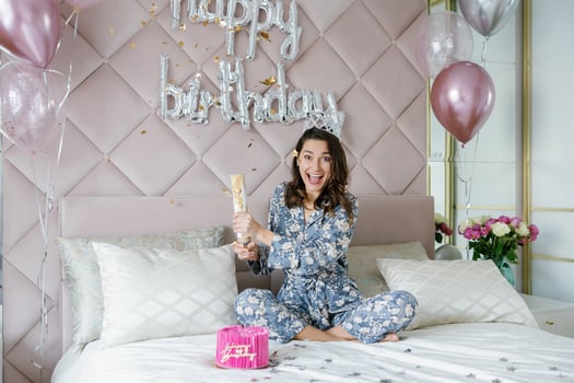 Young woman celebrating birthday opening firecracker on bed photo