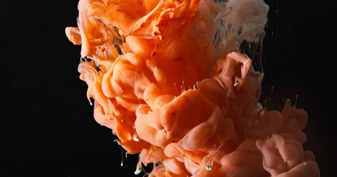 Orange ink in water on black background photo