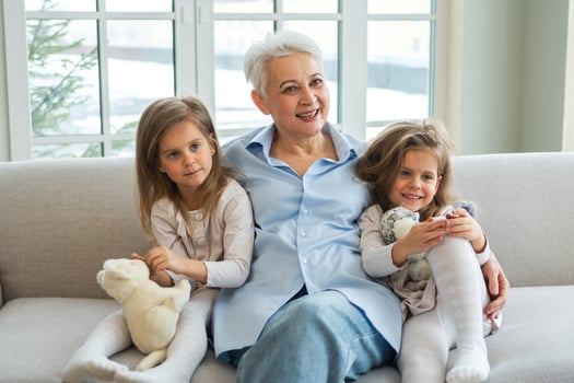 Happy family at home. Two little girls sisters twins grandmother enjoying time together. Good time at home. Grandma granddaughters child kids emotional bonding hugging together. Family generations photo