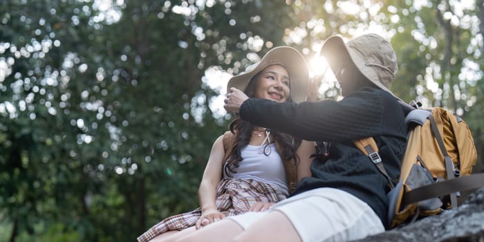 LGBT couple sharing a tender moment while hiking in a sunlit forest photo