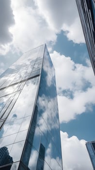 A detailed vertical shot of a modern glass building, reflecting soft clouds in its surface, leaving plenty of empty space for text. photo