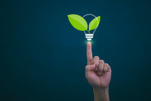 hand holding green leaf light bulb with light bulb on dark background photo