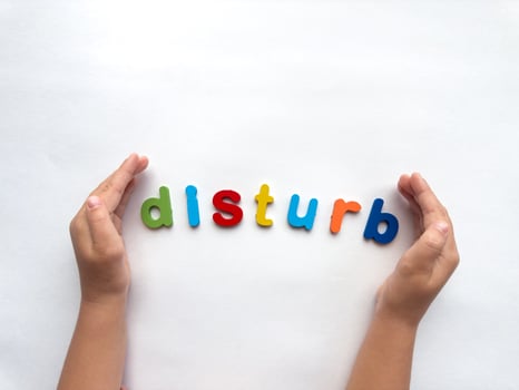 Hands arranging colorful letters spelling disturb on white background photo