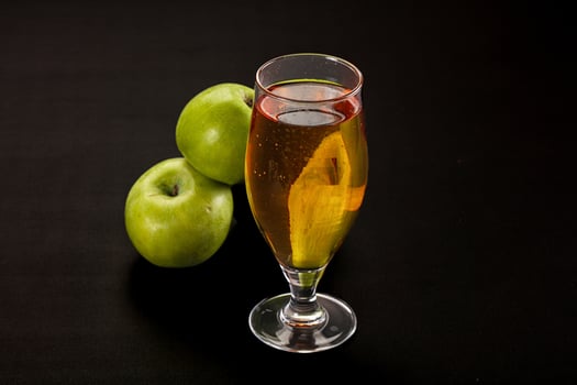 A glass of liquid with a slice of apple on top photo