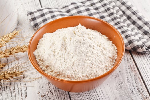 Wheat flour in a bowl and a glass of milk on a wooden table photo