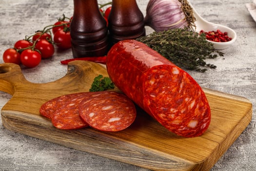 A cutting board with a sausage and some other ingredients photo