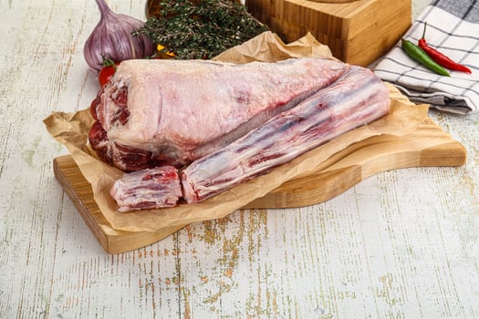 Raw lamb on wooden cutting board with vegetables and spices photo