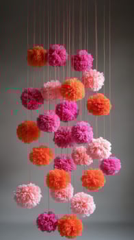 Pink and orange pom poms hanging from strings photo