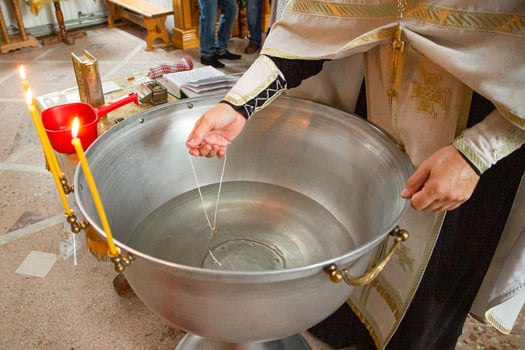 A priest is pouring water into a metal bowl photo