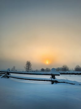 Misty sunrise over the field with wooden fence and village photo