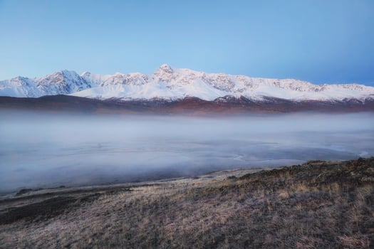 Beautiful nature scene in early autumn mountains. Foggy sunrise on the Dzhangyskol lake, Travel and winter vacation background. photo