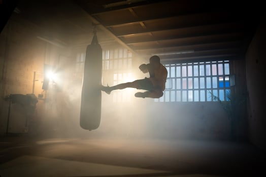 Aerial flying kick Kickboxing or martial arts fighter punching bag in the gym. photo