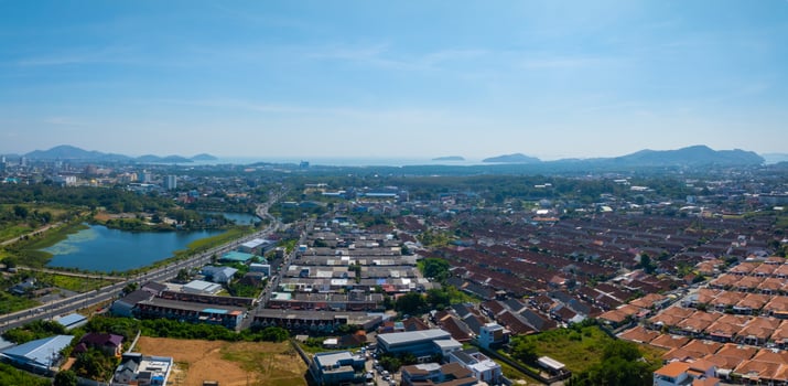 Aerial view of Phuket, Thailand, featuring a lotus pond, urban buildings, distant hills, and the Andaman Sea with islands under a clear blue sky. photo