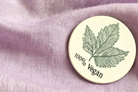 Vegan Badge on Purple Fabric EcoFriendly Symbol of PlantBased Lifestyle photo