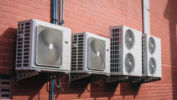 Three air conditioners on a brick wall photo