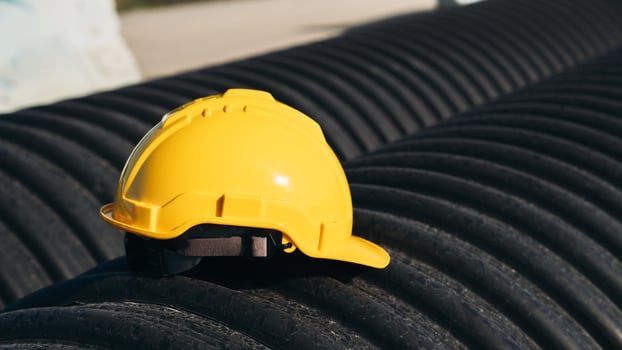 A yellow hard hat sits on top of a pipe photo