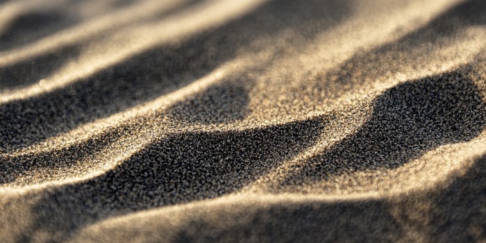 Close-up of sand dunes with rippling patterns and light shadows in a desert landscape. photo