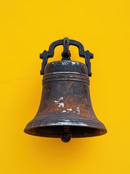 Old rusty bell on a yellow wall photo