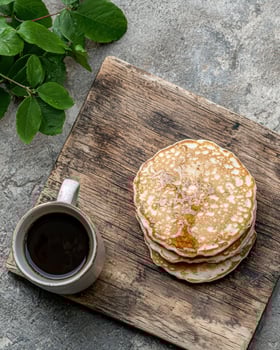 Stack of pancakes with syrup and coffee on rustic wooden board photo