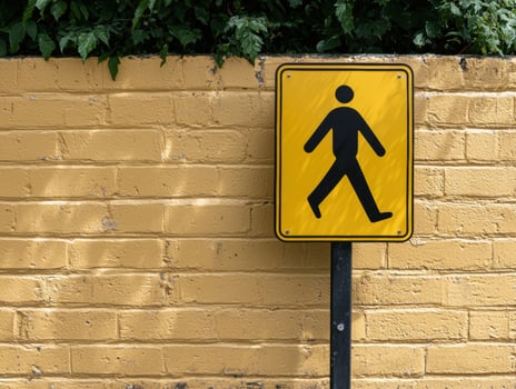 Yellow pedestrian sign on a yellow brick wall photo