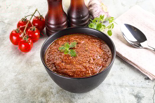 A bowl of tomato sauce with a spoon and a knife photo