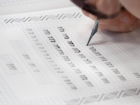 Close-up pupil's hands are writing calligraphy in a notebook. photo