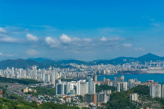 Cityscape panorama coastal high-rise buildings, mountains, clear sky photo