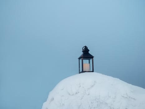old candle lantern stands on the evening snow in frosty winter. photo