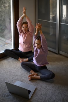A mother and daughter engaging in gymnastics exercises, learning from an online lesson together. photo