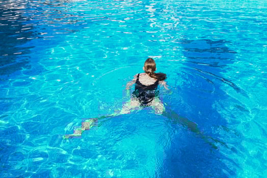 Young woman floating on water in swimming pool with mask on a face photo
