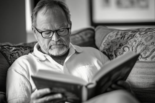 An older man with glasses reading a book photo