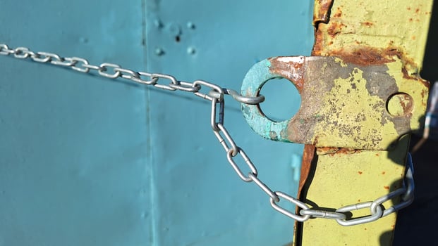 Rusty metal lock with chain on weathered blue background photo