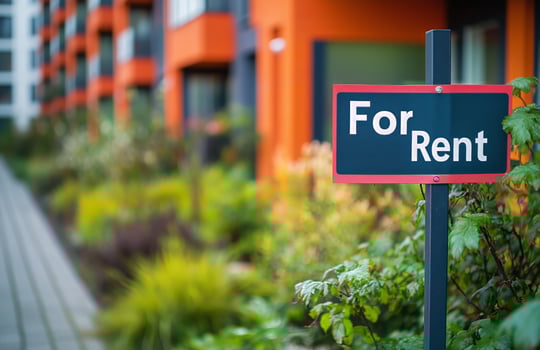 For rent sign in front of modern apartment building with vibrant exterior near green landscaping photo