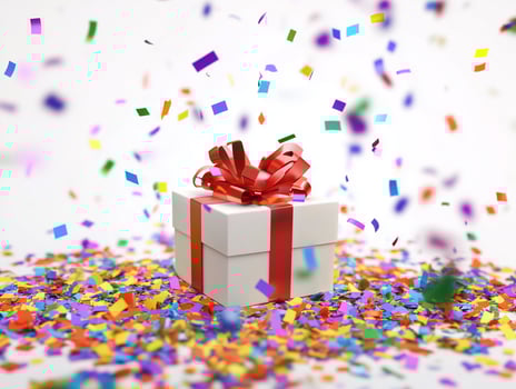 Festive gift box wrapped with red ribbon surrounded colorful confetti. photo